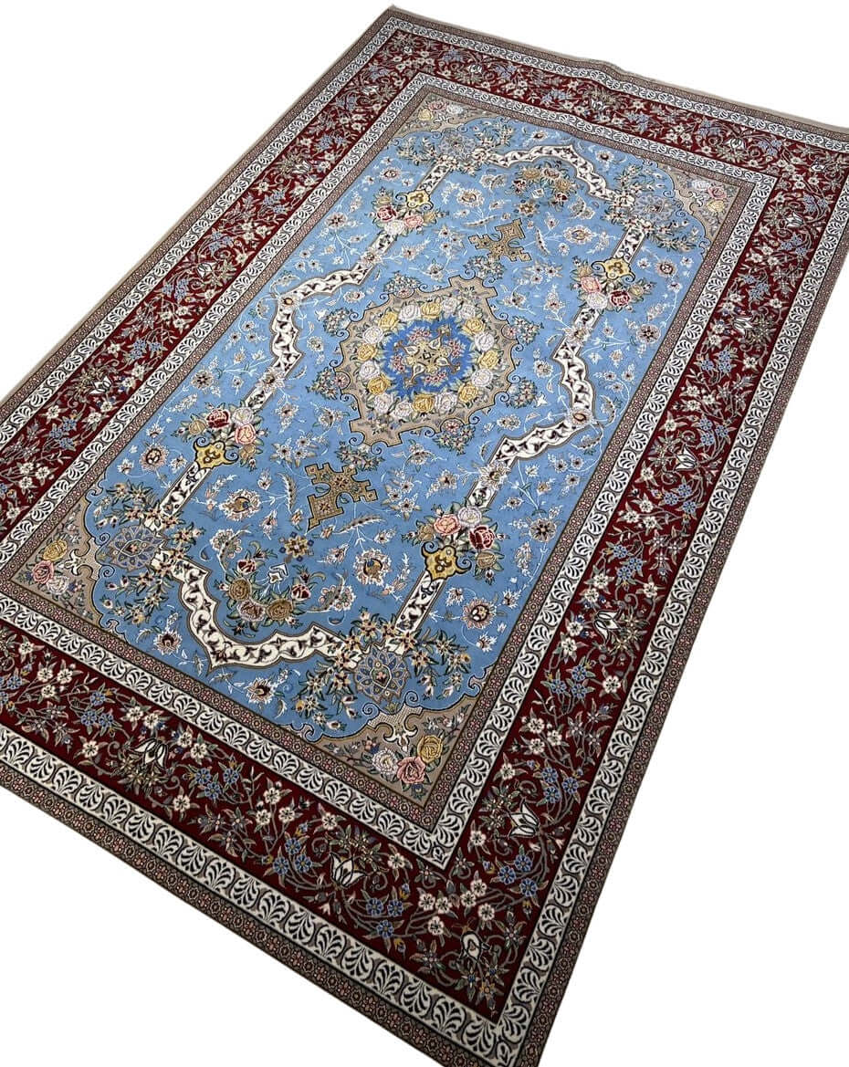 "Traditional Persian rug from Isfahan, featuring intricate medallion design with blue and burgundy accents, made of silk and wool."